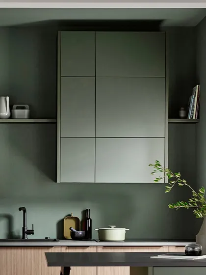 The grid-like design of the upper cabinets in metallic green creates a unique geometric feature, complemented by open shelving for a balanced look.