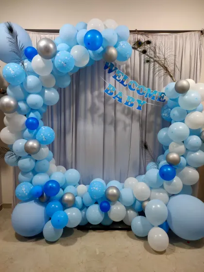 A classic 'Welcome Baby' photo booth for a home celebration. We created a circular balloon arch in shades of blue and white, with peacock feather accents, perfect for capturing memories.