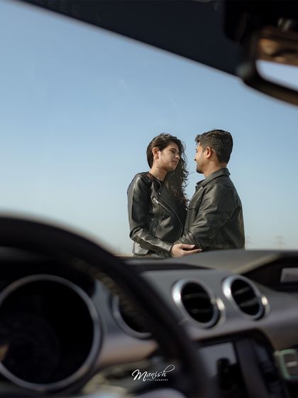 An artistic shot from inside the car, framing the couple against the vast desert sky, creating a sense of intimacy and adventure.