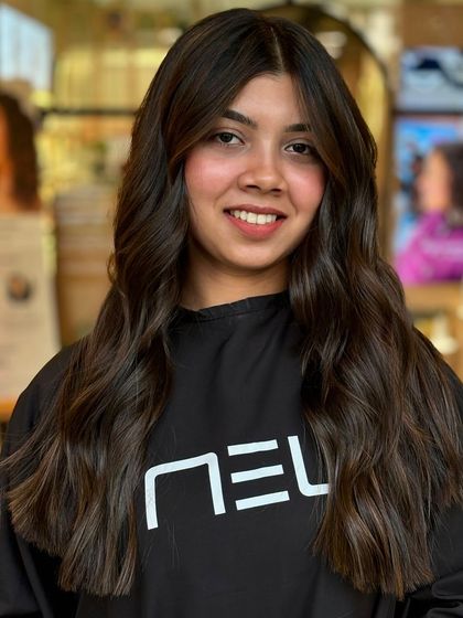 A happy client with her new sun-kissed balayage. The color complements her skin tone, and the soft waves give a relaxed, stylish finish.