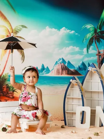 A little girl holding a tiny umbrella in our sunny, tropical beach studio setup.