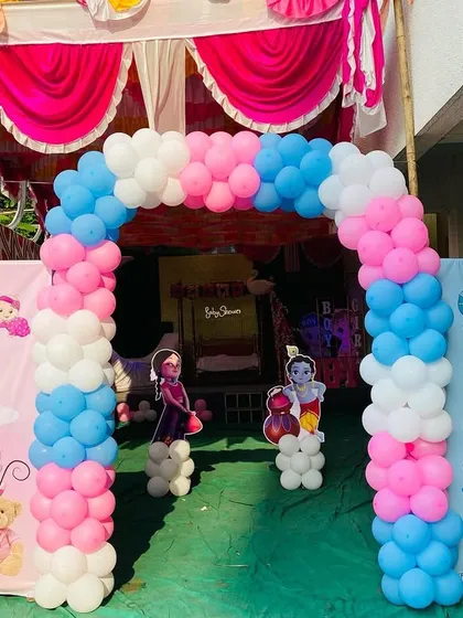 The entrance to a baby shower with a pink, blue, and white balloon arch, perfect for a gender reveal party.