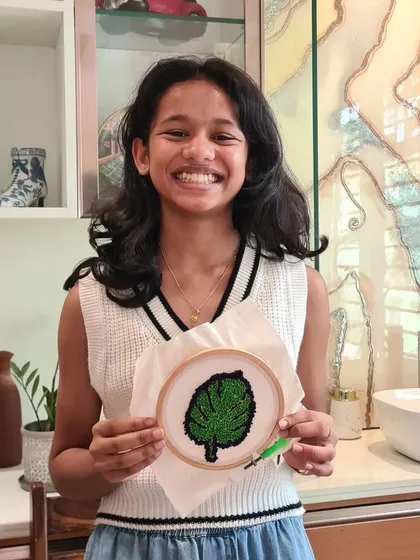 A smiling young artist with her completed green leaf design, ready to be displayed.