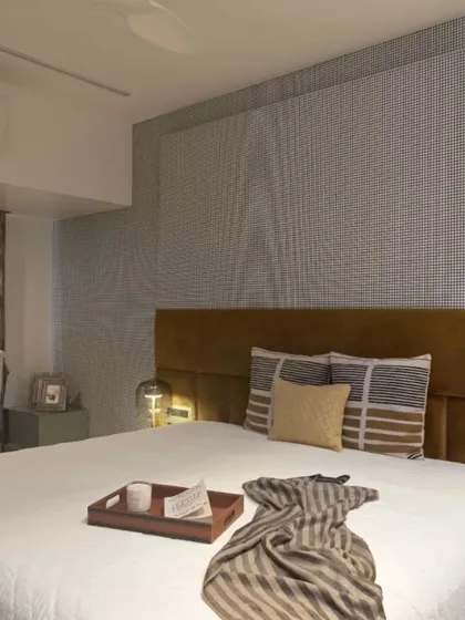 Another view of the master bedroom, showing the full effect of the houndstooth wallpaper and the warm, inviting color palette.