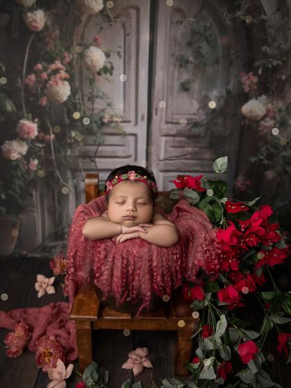 A truly enchanting portrait of a newborn in a bucket, set against a magical, floral backdrop with twinkling lights. This setup creates a fairytale like atmosphere.