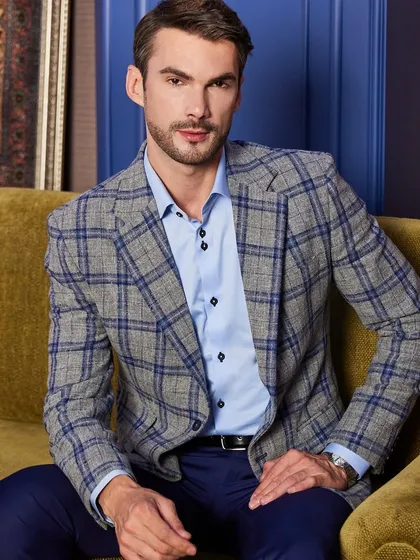 This seated portrait in the plaid jacket shows how the garment maintains its shape. The custom tailoring prevents bunching and ensures a clean line even when relaxed.