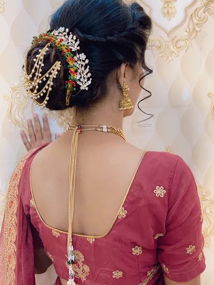 An elegant updo featuring a stunning multi-colored, chained hair accessory. This piece drapes beautifully over the bun and adds a unique, regal touch to the hairstyle.