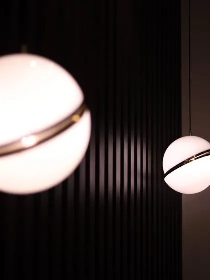 A close-up of modern globe pendant lights with a brass accent ring. We use lighting not just for illumination but as a key decorative element that defines the character of a space.