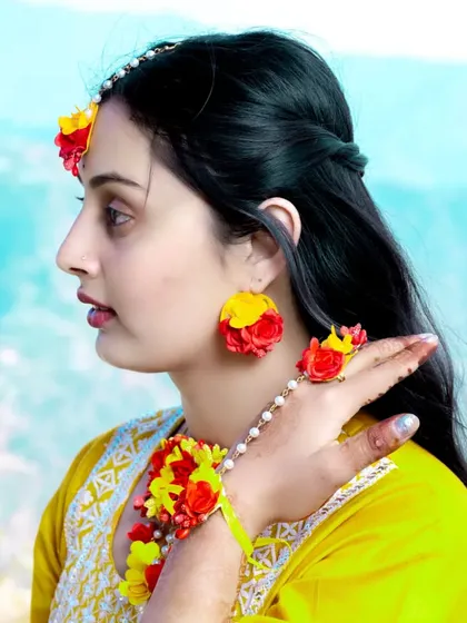A side-profile shot that beautifully captures the details of the bride-to-be's floral earrings and maang tikka.
