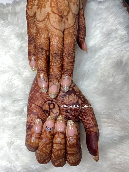 A complete view of the bridal hands, showcasing the beautiful interplay between the mehndi and the custom nail art. The glitter ombré extensions add length and elegance, completing her look.