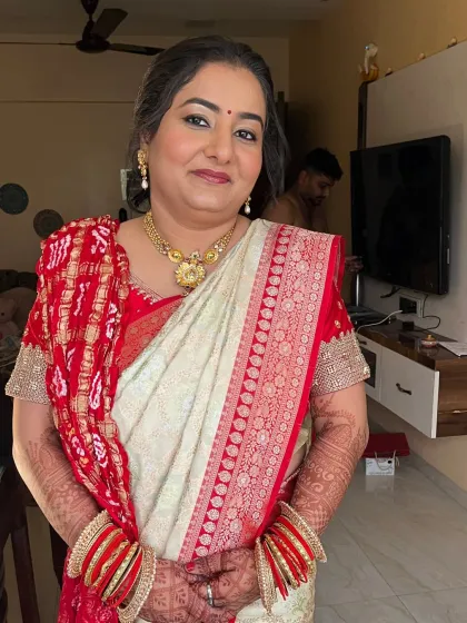 A beautiful wedding guest in a traditional red and white saree. Her makeup is classic, with kohl-rimmed eyes and a matching bindi.