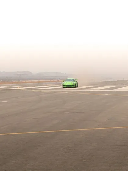 Using negative space to create a sense of scale, this image shows the green Porsche as a small but powerful subject on a vast, empty runway.