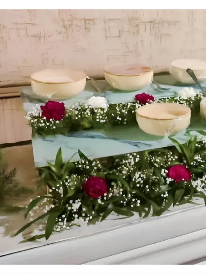 A multi-level dessert station decorated with red and white flowers. The use of varying heights adds dimension and visual appeal to the display.