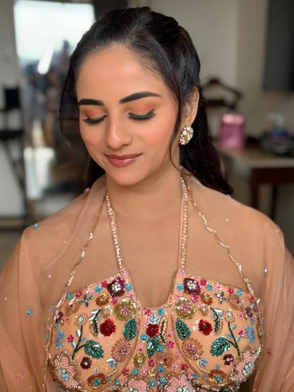 A close-up of the bride's eye makeup, showing the soft peach tones on the lid and the bold green winged liner.