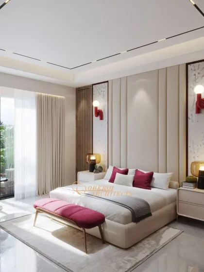 A statement bedroom design that balances a calm, creamy palette with bold pops of berry red. The upholstered wall panels and unique light fixtures add a touch of artistic flair.