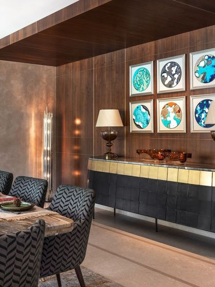 A view of the dining area's custom sideboard with a marble top and brass-finished base. The curated art and lighting complete this sophisticated space for entertaining.