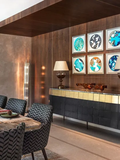 A view of the dining area's custom sideboard with a marble top and brass-finished base. The curated art and lighting complete this sophisticated space for entertaining.