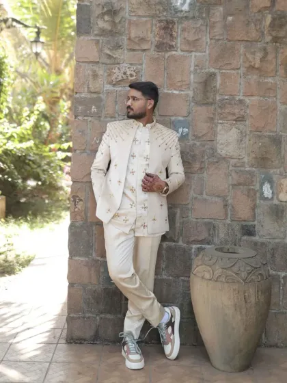 A modern take on wedding wear. This client is styled in a custom-embroidered off-white bandhgala jacket paired with matching trousers and sneakers for a cool, contemporary groom's look.