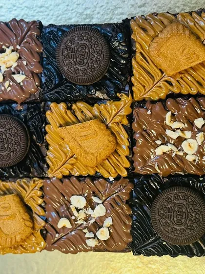 My assorted brownie box is a chocolate lover's dream, offering a variety of textures and flavors in one package. This box features a grid of fudgy brownies topped with Nutella hazelnut, dark chocolate Oreo, and creamy Lotus Biscoff spread.