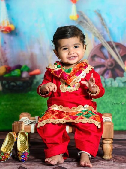 Another adorable shot from the Lohri photoshoot, with traditional juttis placed beside the charpai. The baby's happy expression perfectly captures the festive spirit.