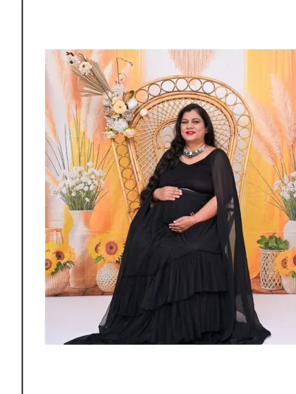 A regal solo portrait in our Boho-themed setup. The mom-to-be is seated on a wicker peacock chair against a warm, sunny backdrop with sunflowers, wearing an elegant black gown.
