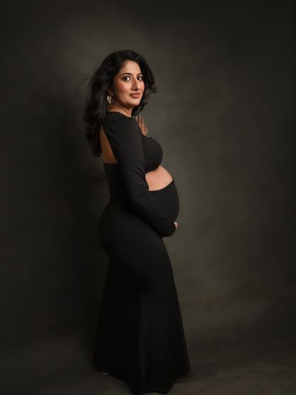 A classic profile shot in a modern black dress with a cutout. This style is both chic and perfect for showcasing your bump.
