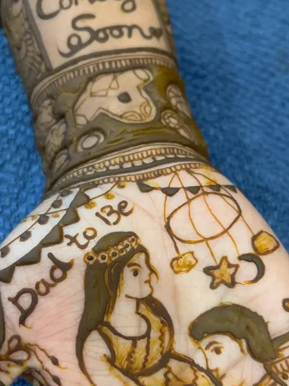 A close-up of the 'Dad to be' portrait and baby mobile details from a custom baby shower mehendi.