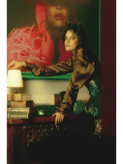 The heroine at a writer's desk, but this time she is in control. The styling, with its mix of satin, sequins, and a corset, is a powerful statement of her reclaimed identity.