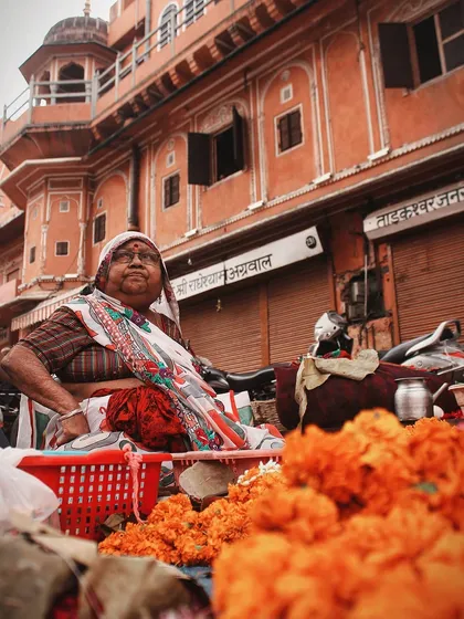 A flower seller in a Jaipur market, surrounded by bright orange marigolds. The colors and her proud expression capture the creative and daring spirit of the local people.