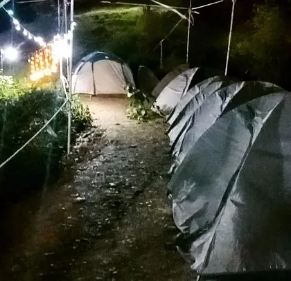 Our campsite transforms at night. Here you can see the tents illuminated by string lights, creating a cozy and inviting path for campers moving through the site.