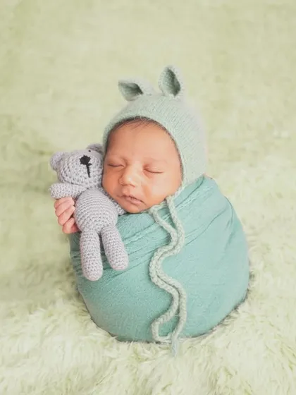 This little bunny is just the cutest! I have a collection of adorable bonnets, headbands, and props to add a touch of personality to your newborn's photoshoot. Here, he's snuggling a tiny teddy bear.