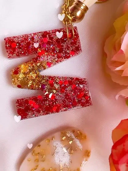 A close-up of the sparkling red and gold glitter inside this 'M' initial keychain. I love adding tiny heart glitters for an extra touch of love.