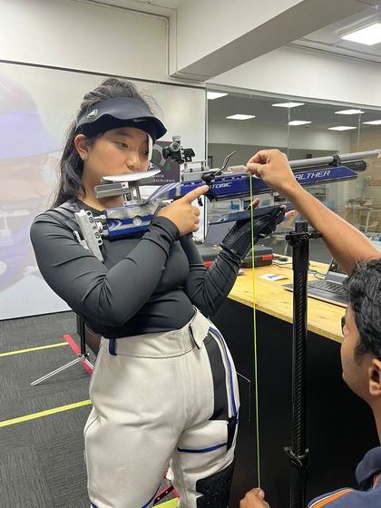 Precision is in the details. Here, a coach makes a fine adjustment to a student's rifle, ensuring her equipment is perfectly calibrated for her stance and style.