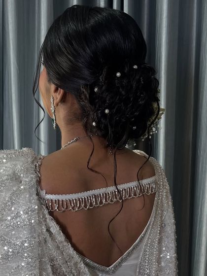 A view of the messy, romantic bun adorned with pearls, complementing the elegant white saree.