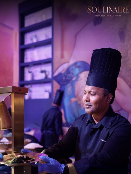 A chef carefully plating a dish at a live station. This image captures the focus and artistry that our culinary team brings to every single plate.