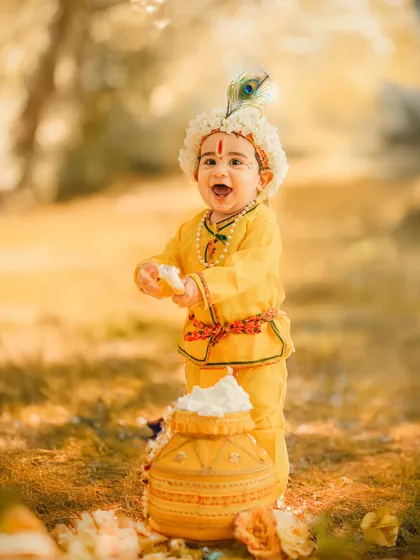 An outdoor Janmashtami shoot with beautiful, soft natural light. This little Krishna enjoys his pot of butter in a lovely park setting, showing our versatility beyond the studio.