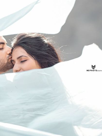 A dreamy and intimate portrait, with the couple wrapped in a flowing white cloth. This artistic shot focuses on their closeness and affection.