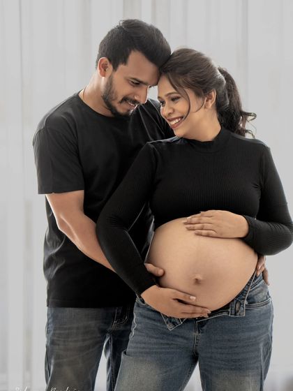 The smiles on their faces say it all. This close-up shot in casual wear captures the warmth and love between the couple as they hold the baby bump together.