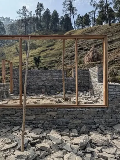 The foundation of a guesthouse is laid with local stone, with the wooden frames for the windows and walls ready to be erected. This image shows the very beginning of the building's journey from the ground up.