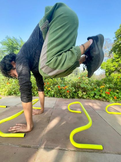Another angle of the creative crow pose, showing the focus and control required to balance on the hands while navigating an obstacle.