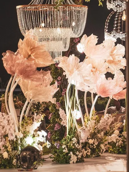 Oversized, handcrafted paper flowers illuminated from within, set against a backdrop of crystal chandeliers. These unique installations served as a beautiful and artistic focal point for the reception.