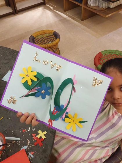 This young artist is showing off the pop-up card she created for Mother's Day, complete with a beautiful 3D floral wreath inside.