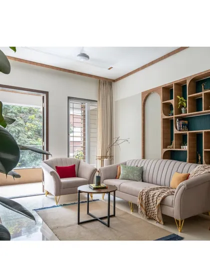 This wide view of the living room highlights the unique, organically shaped bookshelf that serves as both storage and a piece of art. The neutral sofa provides a perfect canvas for colorful cushions.
