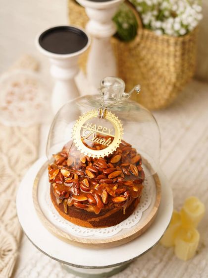 Another look at our festive Almond Praline Teacake under its glass cloche, a popular choice for Diwali gifting.