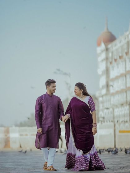A beautiful portrait of a couple in front of the Taj Mahal Palace Hotel. The regal purple outfits complement the iconic architecture, creating a look of modern royalty for this Mumbai pre-wedding shoot.