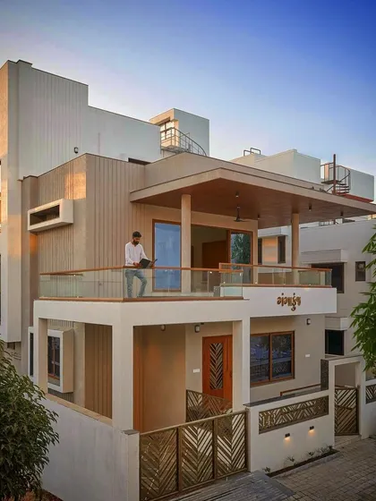 This multi-level residence showcases a complex interplay of volumes. The design features a prominent balcony with a wooden canopy, providing a covered outdoor space and adding depth to the facade.