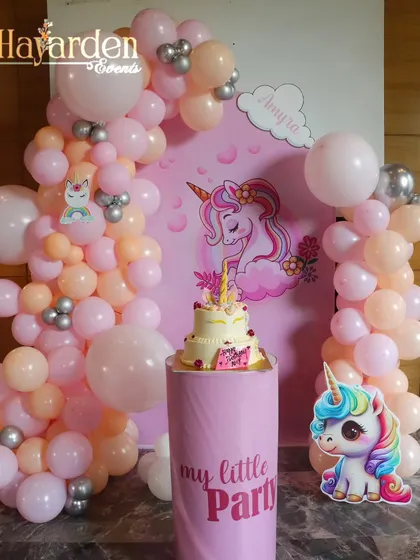 A magical unicorn-themed party with a pastel pink balloon arch and a 'My Little Party' pedestal for the cake.