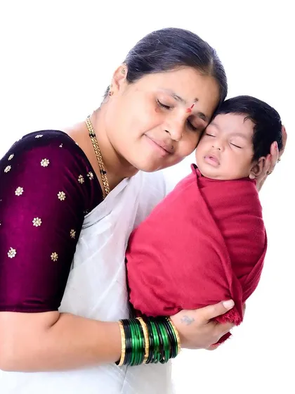 A portrait of a grandmother holding her sleeping newborn.