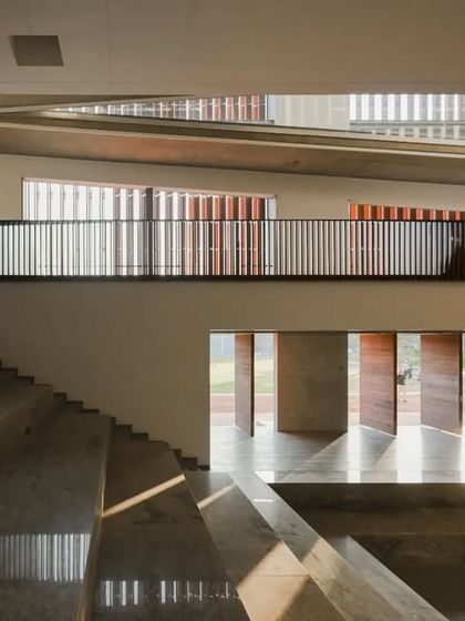 An auditorium-style tiered seating area at the JSW School of Public Policy provides a flexible space for lectures, presentations, and group discussions. The design uses natural materials like stone and wood to create a warm and inviting atmosphere.