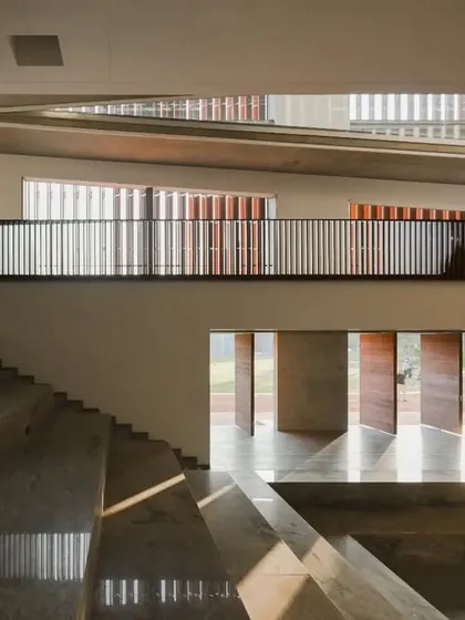 An auditorium-style tiered seating area at the JSW School of Public Policy provides a flexible space for lectures, presentations, and group discussions. The design uses natural materials like stone and wood to create a warm and inviting atmosphere.